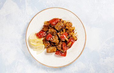meat with vegetables and sauce on a round plate on a blue background top view