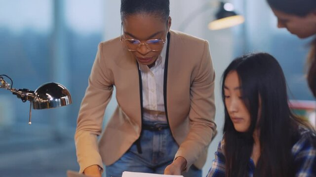 Diverse corporate couple of chinese executive and african american female boss sharing computer project making creative design plans marketing in coworking space.