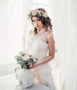 Bride in a wedding dress with a flower wreath. Beautiful tender morning with a decor of flowers