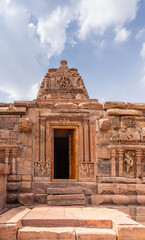 Obraz premium Bagalakote, Karnataka, India - November 7, 2013: Pattadakal temple complex. Front facade with sculpted doorway of brown stone Jambulingeshwara temple under blue cloudscape.