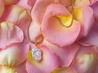 Luxury elegant baroque pearl pendant with golden chain on pink yellow rose petals