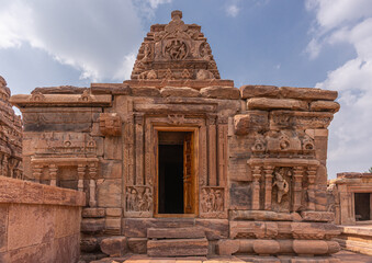 Fototapeta premium Bagalakote, Karnataka, India - November 7, 2013: Pattadakal temple complex. Front side with sculpted doorway of brown stone Jambulingeshwara temple under blue cloudscape.
