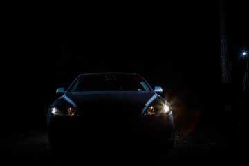 the headlights of an expensive car shine in the dark