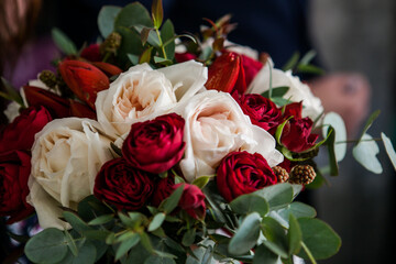 a beautiful and expensive bouquet with red and white roses and eucalyptus greens and raspberries