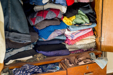 Closet clogged with clothes and textiles. Second hand reuse. Decluttering and cleaning the cabinet