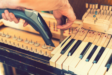 Setting up an old piano. The master repairs an old piano. Deep cleaning the piano. Hands of professional worker repairing and tuning an old piano. toned © jollier_