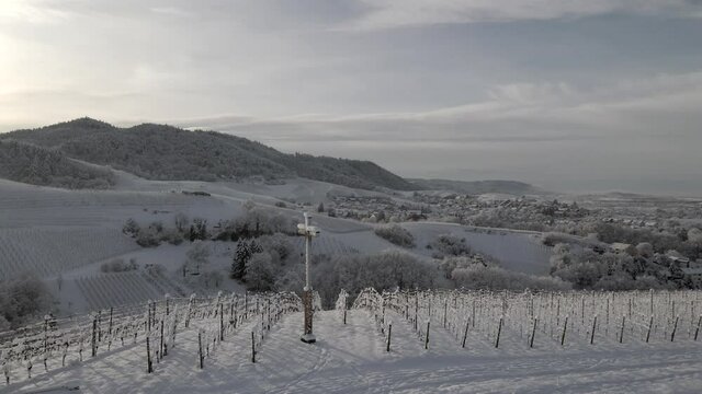 Drone Orbiting At Cross Situated On Snowy Vineyard With Trellis Near Zell-Weierbach In Offenburg, Germany. - aerial