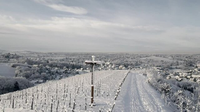 Snowy Cross At Vineyard Plantation With Mountains During Winter In Offenburg, Germany. - aerial