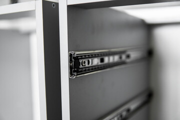 Stainless telescopic bayonet drawer slide guides, installed on a kitchen cabinet from gray...