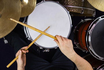 Professional drum set closeup. Man drummer with drumsticks playing drums and cymbals, on the live...