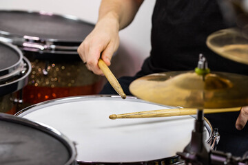 Professional drum set closeup. Man drummer with drumsticks playing drums and cymbals, on the live music rock concert or in recording studio   