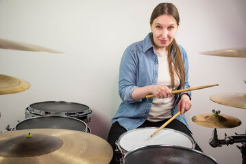 Professional drum set closeup. Beautiful young girl drummer with drumsticks playing drums and...