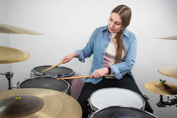 Professional drum set closeup. Beautiful young girl drummer with drumsticks playing drums and cymbals, on the live music rock concert or in recording studio. Female drummer.