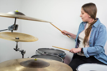 Fototapeta na wymiar Professional drum set closeup. Beautiful young girl drummer with drumsticks playing drums and cymbals, on the live music rock concert or in recording studio. Female drummer.