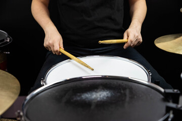 Professional drum set closeup. Man drummer with drumsticks playing drums and cymbals, on the live music rock concert or in recording studio   