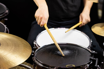 Professional drum set closeup. Man drummer with drumsticks playing drums and cymbals, on the live music rock concert or in recording studio   