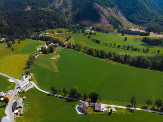 Aerial view over green meadow in Zgornje Jezersko, to Kamnik-Savinja Alps on a sunny summer day in Slovenia. Travel and tourism.