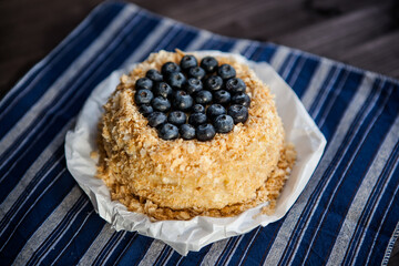 homemade cake decorated with crumbs and blueberries on a dark background