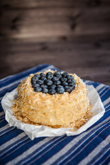 homemade cake decorated with crumbs and blueberries on a dark background