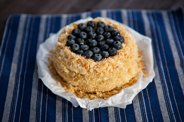 homemade cake decorated with crumbs and blueberries on a dark background
