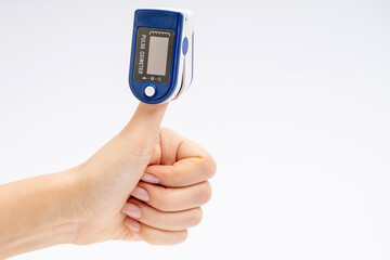 Finger pulse oximeter. On white background. The device is put on the thumb up. Health diagnostics
