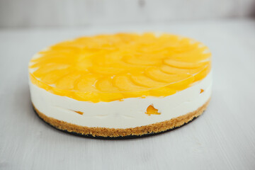 classic homemade cheesecake with a fruity yellow filling on top on a light background