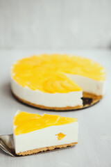 a slice of classic homemade cheesecake with a fruity yellow filling on top on a light background