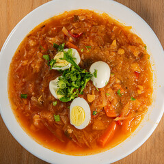 Ukrainian borscht in a plate with boiled chicken egg wedges.