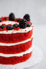 homemade red velvet cake decorated with berries on a light wooden background