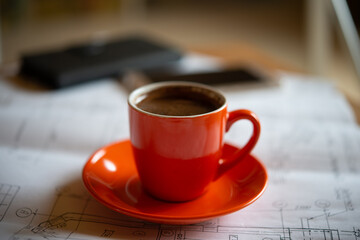 Cup With Coffee on a Plate in the Workroom Stands on the Drawings. Web Banner.