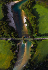 Aerial top down view of the railway connection. Summer, sunny weather. Metal bridge over a mountain river. Transport and freight transportation concept. Vertical photo. Misace, Slovenia.