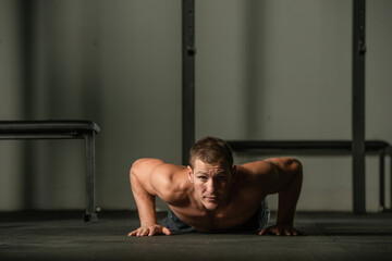 Fototapeta na wymiar Strong male athlete doing push-ups indoors. Close up perspective, healthy lifestyle, fatless body.