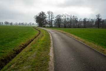 Fototapeta na wymiar Slatsdijk (Swamp Dike) running through the fields surrounding Loenen, at the edge of Veluwe and IJsselvallei (IJssel Valley) in The Netherlands