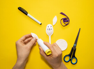 Making Easter bunny from plastic spoon and cotton pad on yellow background. Homemade easy children's craft. Simple creative art project.Step by step instructions.Decor for spring. DIY concept. Step 4