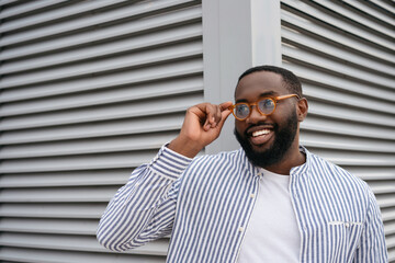Portrait of confident smiling African man wearing stylish eyeglasses isolated on grey background	