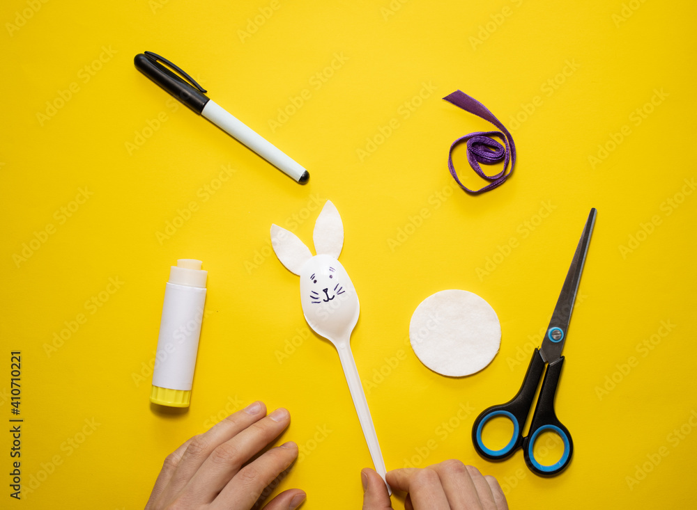 Wall mural making easter bunny from plastic spoon and cotton pad on yellow background. homemade easy children's