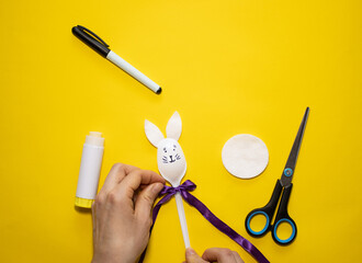 Making Easter bunny from plastic spoon and cotton pad on yellow background. Homemade easy children's craft. Simple creative art project.Step by step instructions.Decor for spring. DIY concept. Step 6