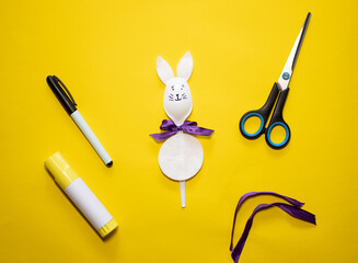 Making Easter bunny from plastic spoon and cotton pad on yellow background. Homemade easy children's craft. Simple creative art project.Step by step instructions. DIY concept. Final result