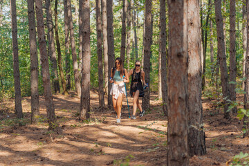 Fototapeta premium Two female caucasian friends hiking in the woods on a mountain on a nice sunny day.