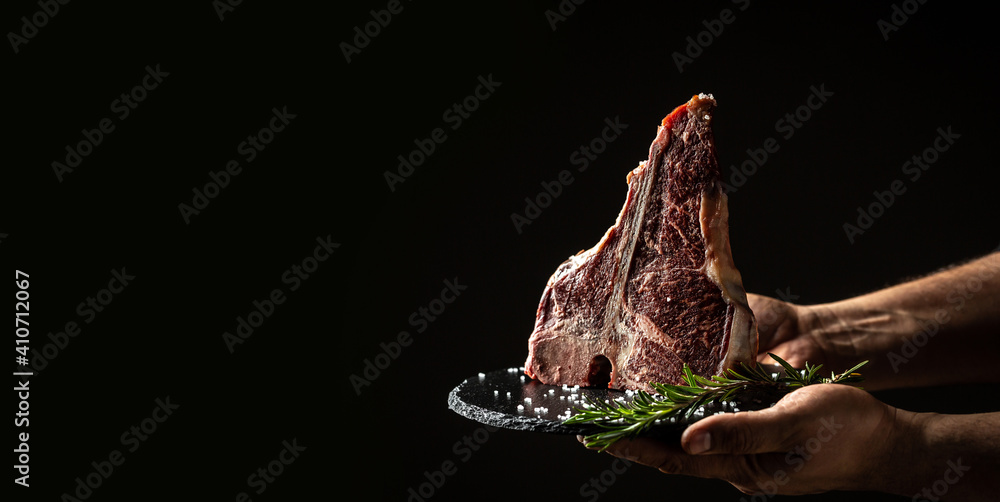 Wall mural cook hands with big raw t-bone or aged wagyu porterhouse grilled beef steak with spices ready to coo