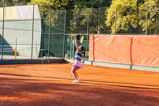 A Young Female Tennis Player Serving On A Clay Court