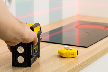 A professional checks the angles while taking measurements of the kitchen