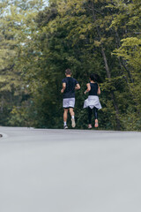 Athletic couple running on a street next to each other. Nature,fit and healthy concept.