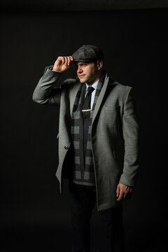 in a coat and a cap a scarf Young male three piece suit business man, attractive isolated standing. Beautiful city, fashionable elegance background black bodybuilder