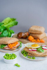 Healthy sandwiches or burgers with whole grains bread, microgreens, egg, fresh vegetables Ketogenic diet, intermittent fasting, weight loss. Breakfast and dieting time concept. White table, copy space