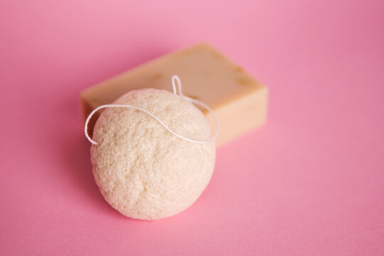 Natural cosmetics on pink background. Flat lay top view skin care products branding mock up. Natural konjac sponge and natural hand made soap. Healthy lifestyle, zero waste cosmetic routine. 