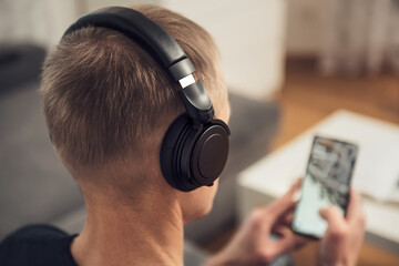 The man in headphones and with a smartphone. Back view.