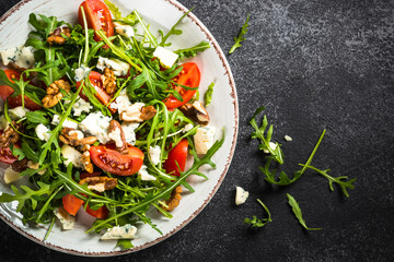 Arugula salad with tomatoes, blue cheese and walnuts. Healthy vegetarian dish. Top view image.