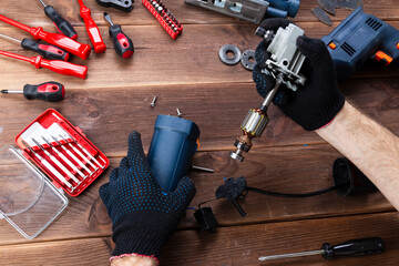 Power tool repair. Details of electrical appliance and repair tools on a wooden table in a repair shop