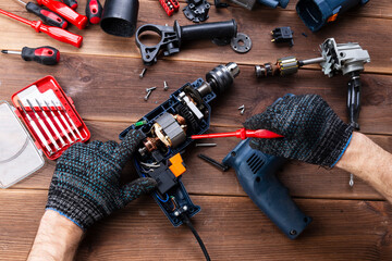 Power tool repair. Details of electrical appliance and repair tools on a wooden table in a repair...